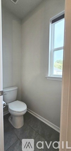 A bathroom with a toilet and a window.