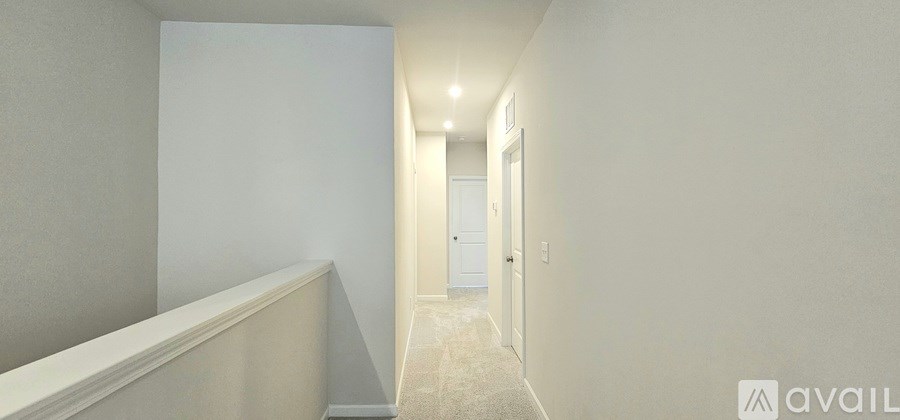 A long hallway with a carpeted floor and white walls.