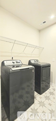 Two black microwaves are placed on a tiled floor.