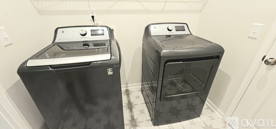 Two black front loading washing machines in a small room.