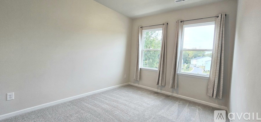 A room with two windows and carpeted floor.
