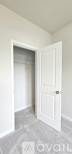 A white door is open to a room with a grey carpet.