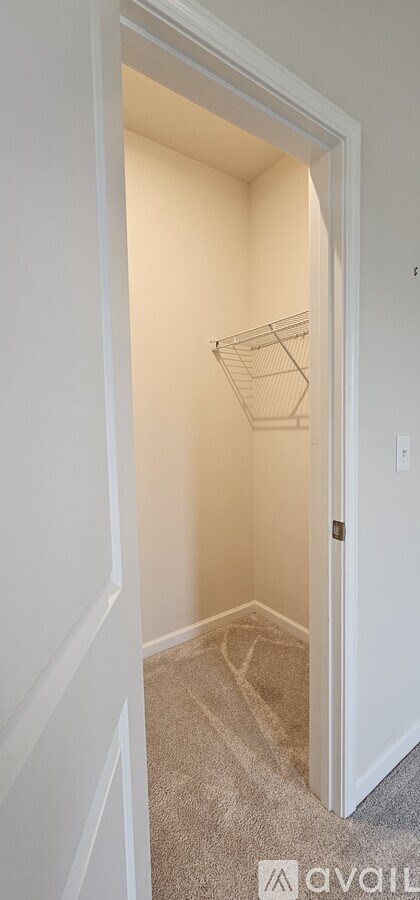 A white doorway leads to a small, empty room with a carpeted floor.