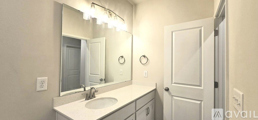 A bathroom with a sink, mirror, and lighting fixture.