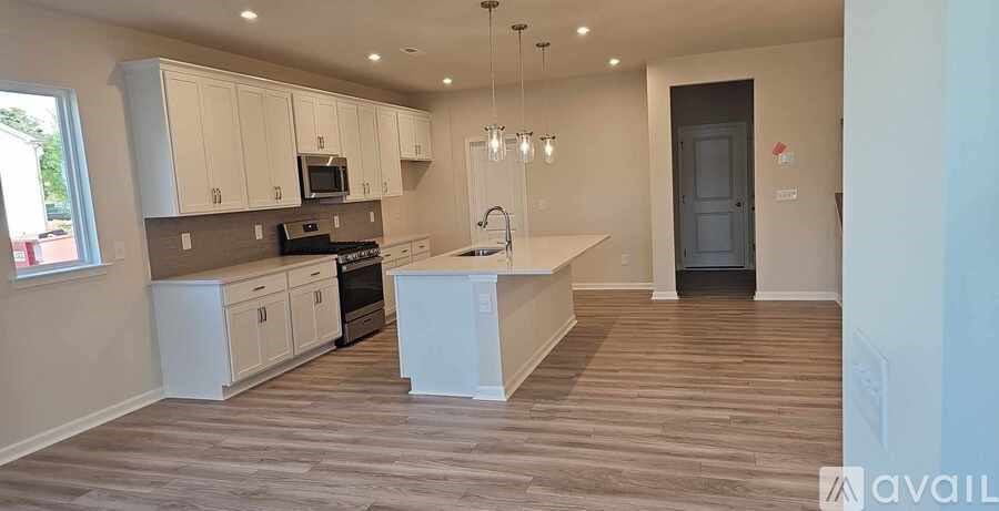 A kitchen with white cabinets and a wooden floor.