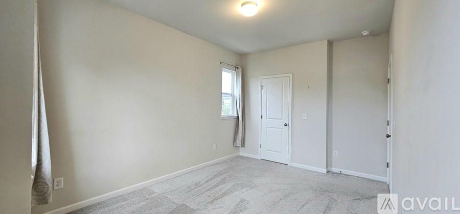 A spacious room with a door, window, and a carpeted floor.