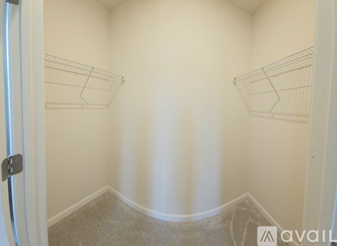 A small, empty room with a carpeted floor and two wire shelves on the wall.