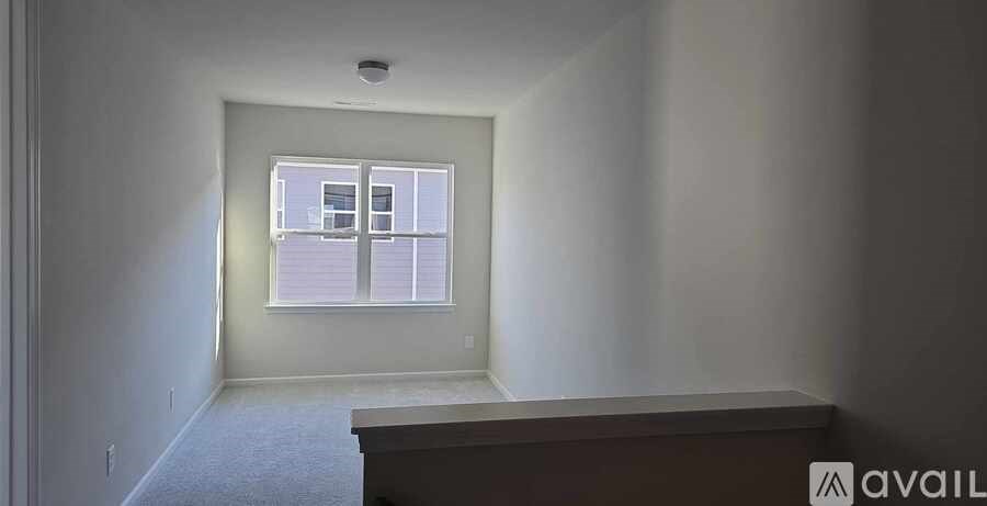 A room with a window and a carpeted floor.