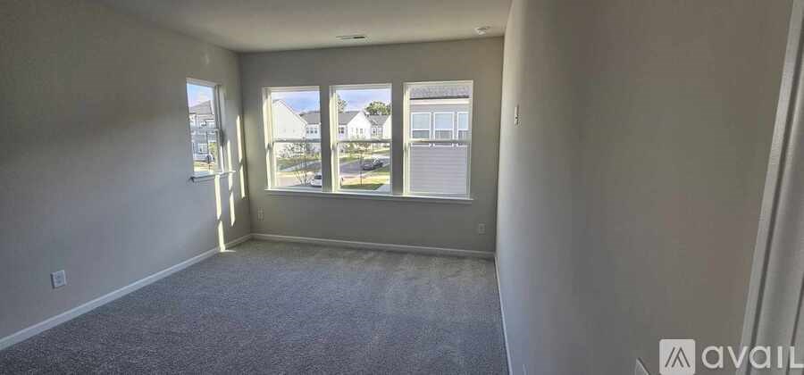 A room with a carpeted floor and a window overlooking a street.