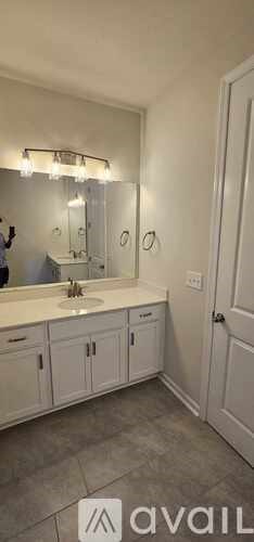 A bathroom with a sink, mirror, and cabinets.