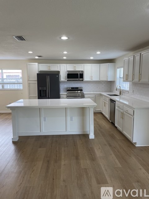 A kitchen with white cabinets and a black fridge.