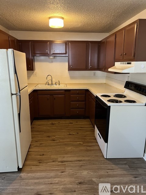 A kitchen with white appliances and brown cabinets.