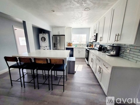 A kitchen with a table and chairs in the foreground and a washing machine in the background.