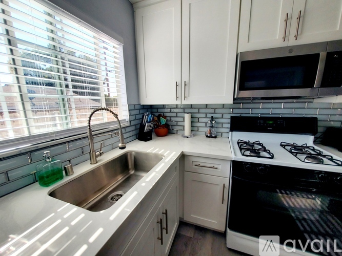 A kitchen with a stove, sink, and cabinets.