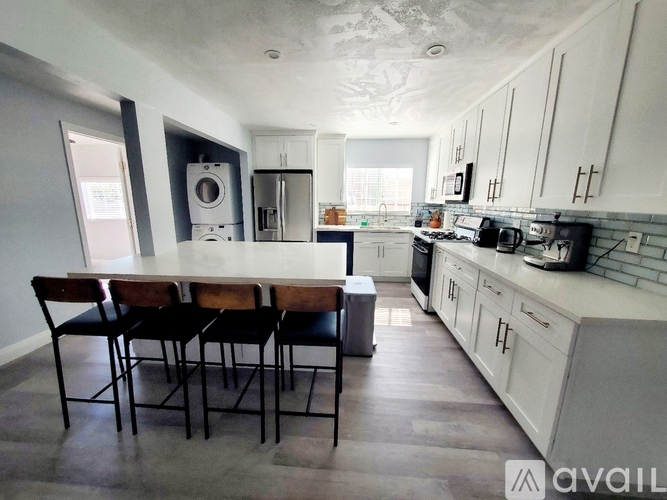A kitchen with a table and chairs in front of a washing machine and a refrigerator.