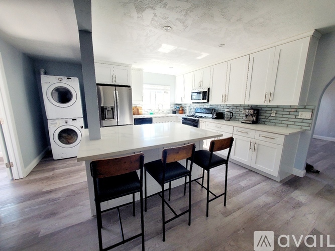 A kitchen with a white countertop and a washing machine in the corner.