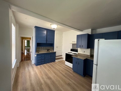 A kitchen with blue cabinets and a white refrigerator.
