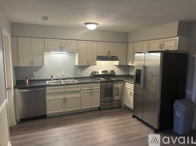 A kitchen with a black fridge and stainless steel appliances.