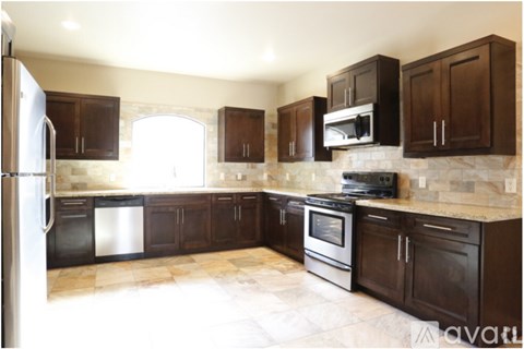 A kitchen with dark brown cabinets and a tiled floor.