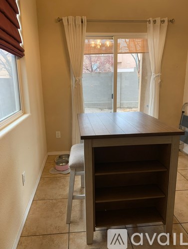 A kitchen island with a bar stool in front of a sliding glass door.