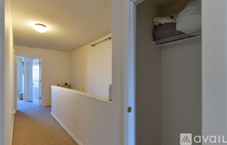 A room with a white wall and a small closet with a shelf.