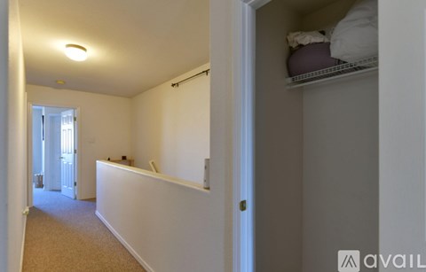 A room with a white wall and a small closet with a shelf.