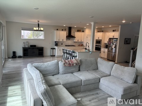 A modern living room with a grey sectional sofa and a kitchen in the background.