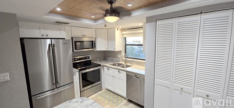 A kitchen with a refrigerator, microwave, oven, and sink.