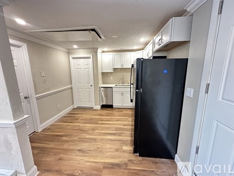 A kitchen with a black fridge and wooden floors.