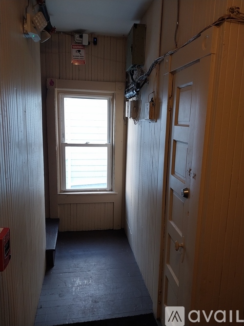 A narrow hallway with a door on the right and a window on the left.