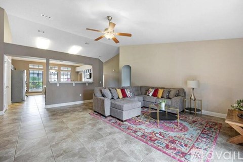 A living room with a grey couch and a rug.