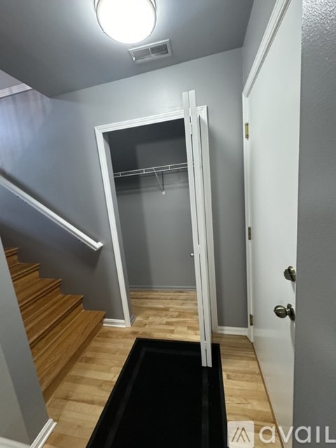 A hallway with a staircase and a door leading to a bathroom.