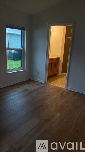 A room with wooden floors and a window overlooking a fence.