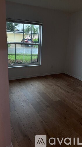 A room with wooden flooring and a window overlooking a street.