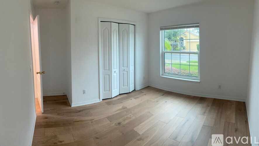 A room with a sliding door and a window overlooking a lawn.