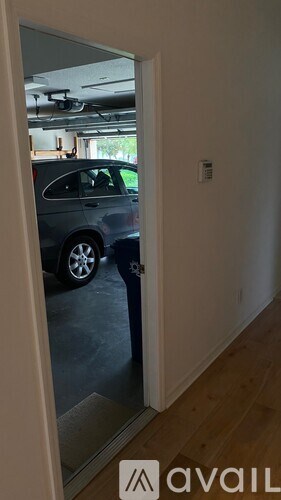 A car is parked in a garage visible through a glass door.