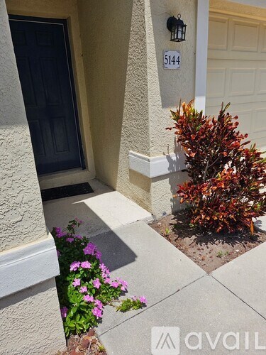 A house numbered 5144 with a black door and a small garden in front.