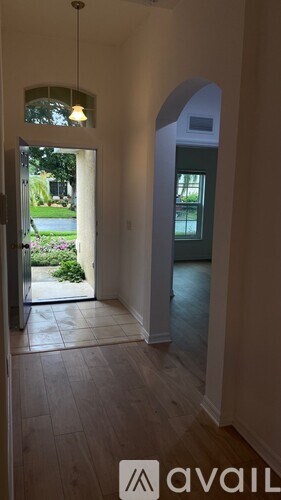 A hallway with a wooden floor and a hanging light fixture.