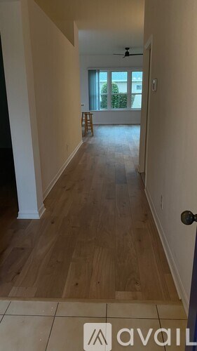 A long hallway with a door on the right and a balcony with a blue curtain in the distance.