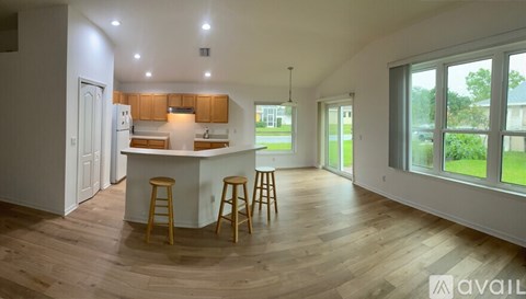 A kitchen with wooden floors and a bar area with stools.