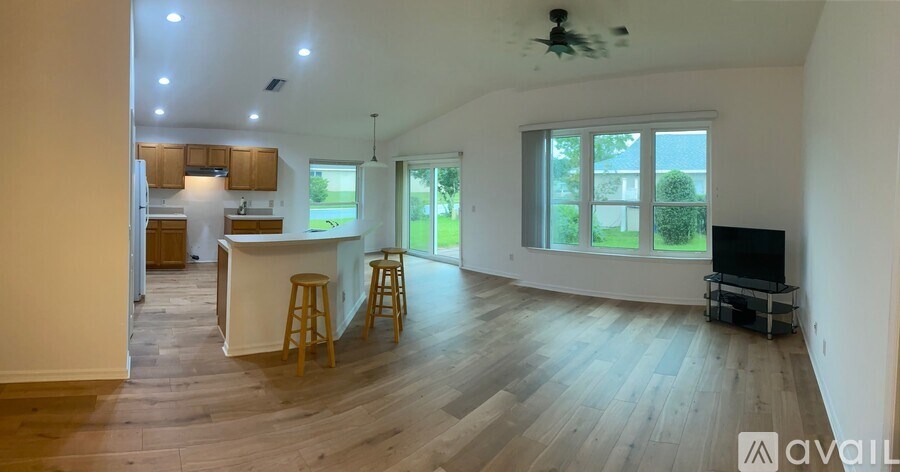 A spacious kitchen and living room with wooden floors and a ceiling fan.