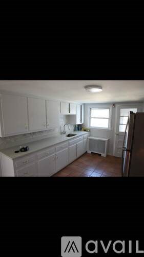 A kitchen with white cabinets and a refrigerator.
