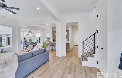 A spacious living room with a grey sofa and a ceiling fan.