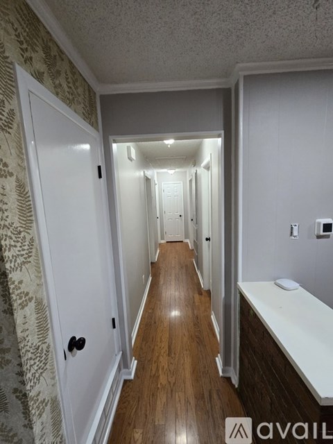 A hallway with wood floors and white walls.
