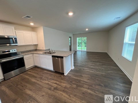 A kitchen with white cabinets and a wooden floor.