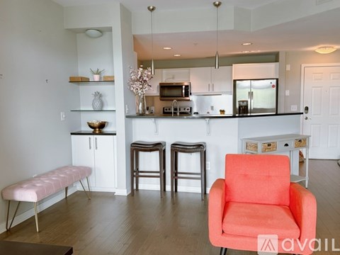 A bright orange chair sits in a modern kitchen with white cabinets and a black counter.
