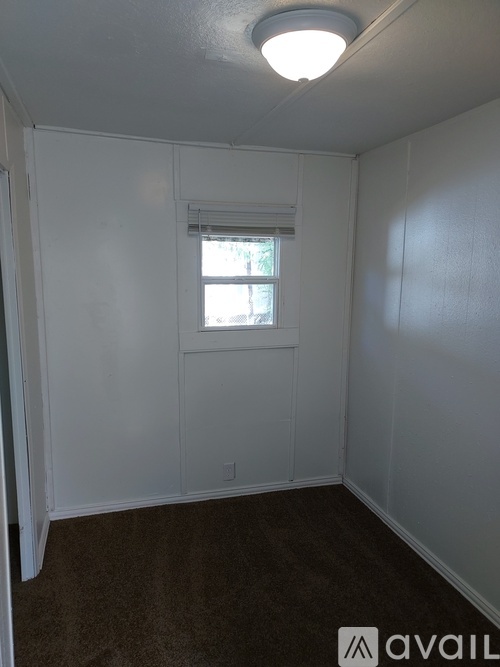 A small room with a window and carpeted floor.