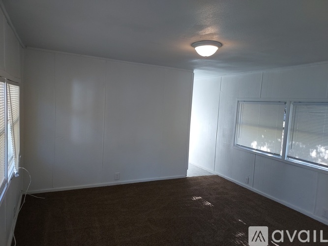 A room with white walls and a window with blinds.
