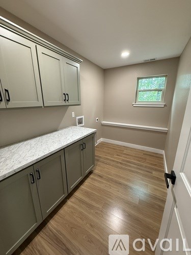 A kitchen with wooden floors and grey cabinets.