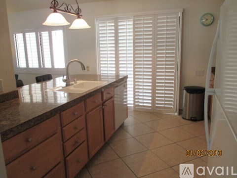 A kitchen with a marble counter top and wooden drawers.